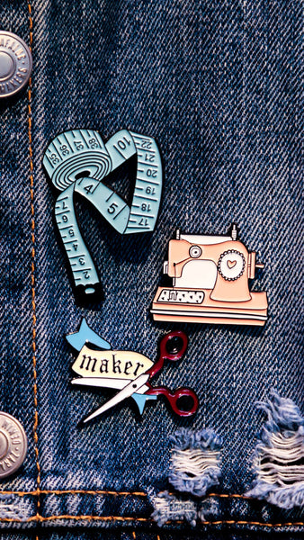Pin's Couture : machine à coudre rose, mètre ruban bleu et paire de ciseaux "Maker"