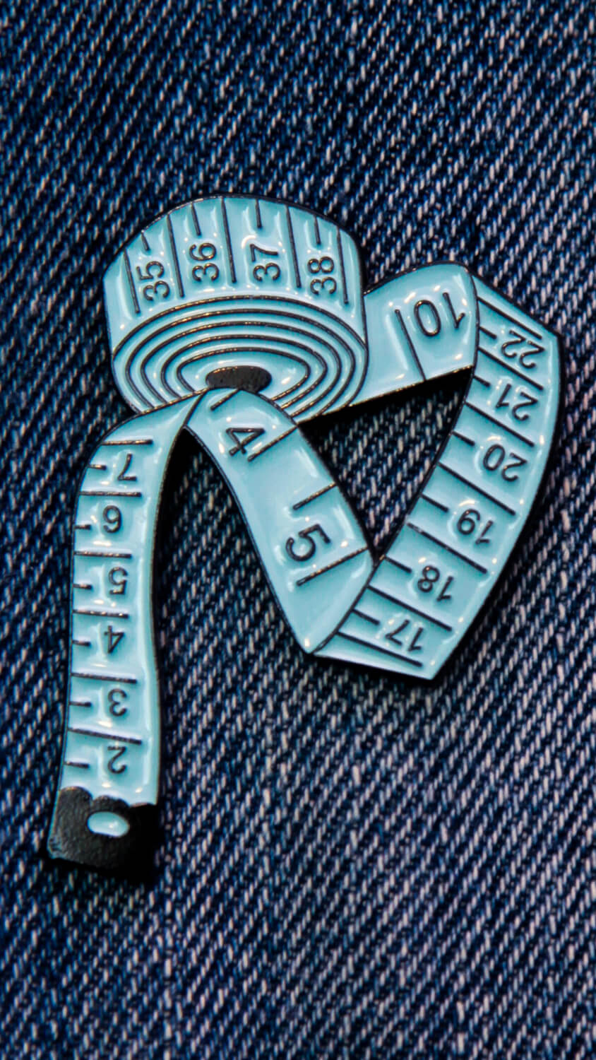 Pin's couture représentant un mètre ruban bleu.